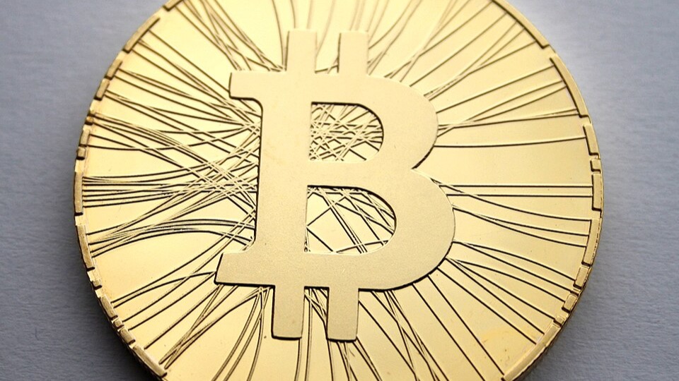 Physical cryptocurrency coin held in front of a laptop keyboard